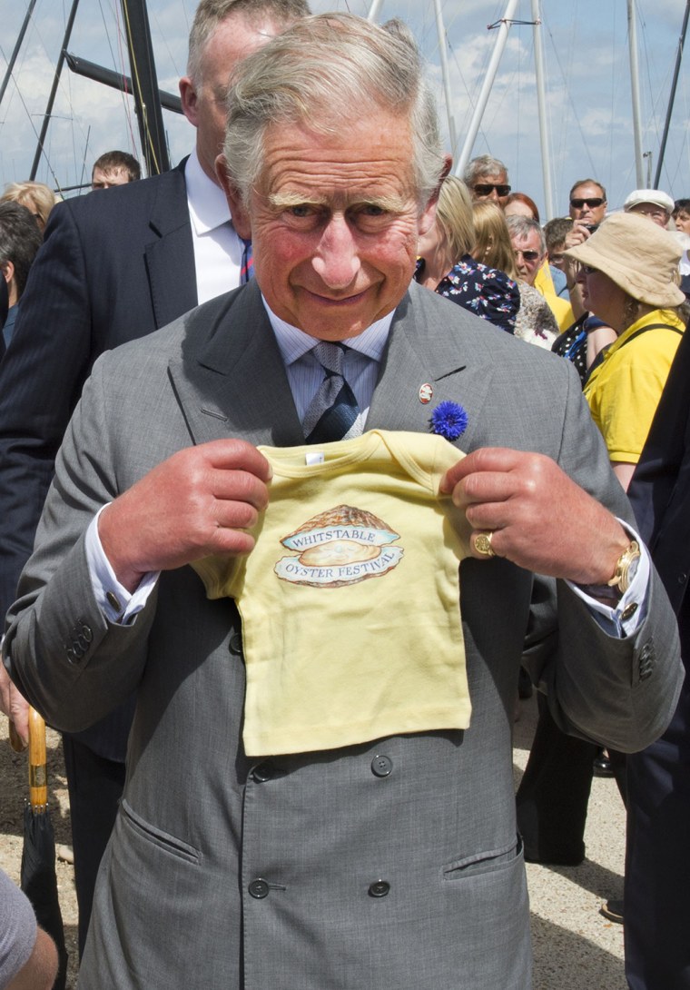 Britain's Prince Charles, the Prince of Wales poses while holding a childs T-shirt during a visit to the Whitstable Oyster Festival in Whitstable on J...