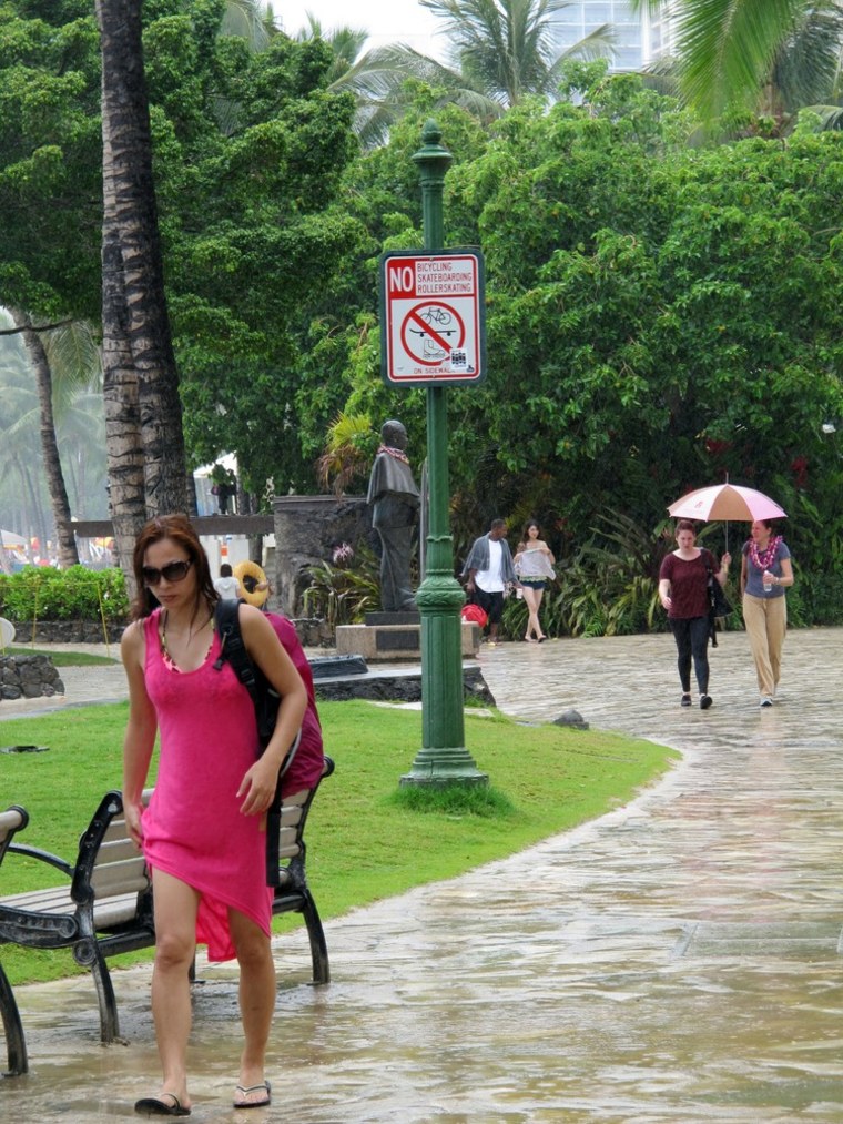 Pedestrians walk along Waikiki beach in Honolulu on Monday, July 29, 2013 as Tropical Storm Flossie approached Hawaii.