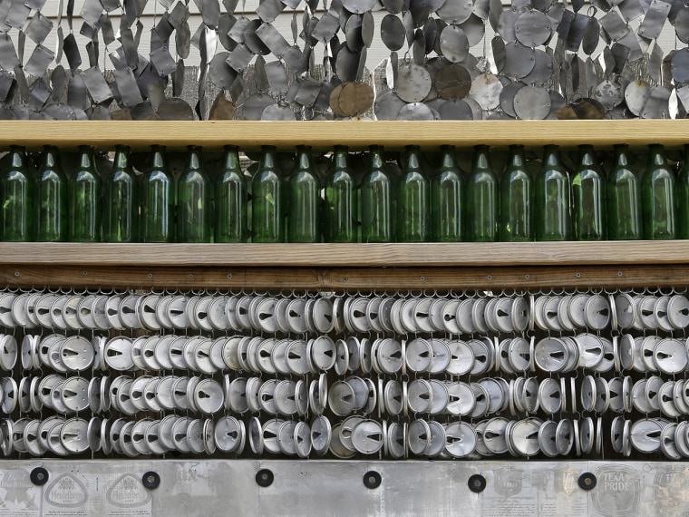 Beer bottles and different parts of beer cans line a fence in the yard of the beer can house, a Houston landmark,  Wednesday, July 10, 2013. Former ow...