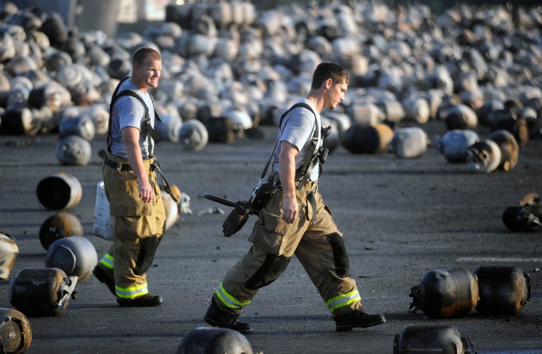 Firefighters walk among thousands of exploded propane cylinders that litter the storage yard of a propane plant in Tavares, Fla., on July 30.