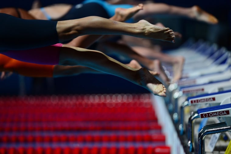 Participants jump as they compete in the heats of the Women's 200m freestyle swimming event.