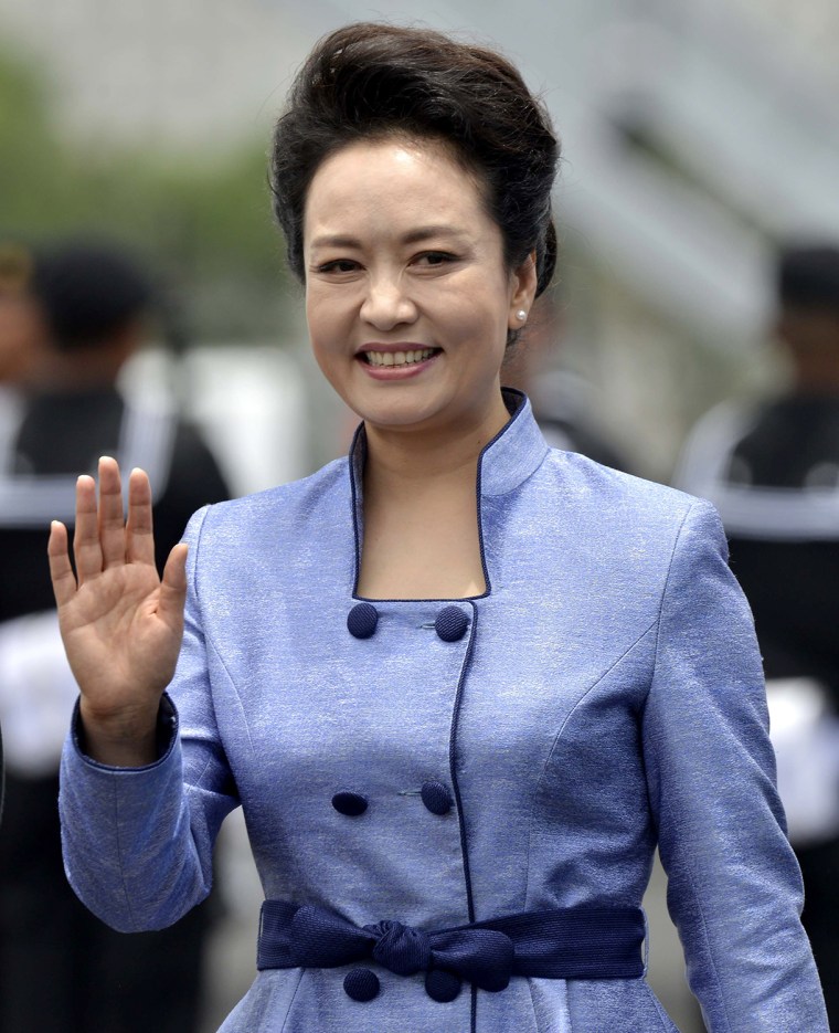 Chinese First Lady Peng Liyuan, wife of Chinese President Xi Jinping, waves at the reception committee upon their arrival at the airport on June 4, 20...