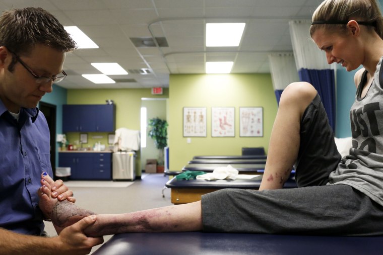 Boston bombing survivor Rebekah Gregory, right, winces in pain during a physical therapy session on July 25, 2013, in Katy, Tex., as her damaged leg, ankle and foot are massaged by physical therapist Andrew Hyde to help break up scar tissue and get the injured area moving again.