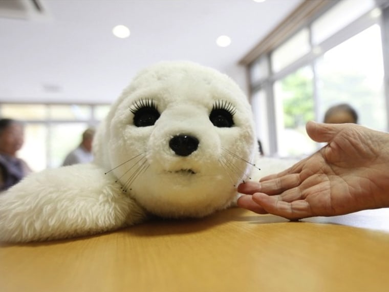 In this combination picture, a therapeutic robot named Paro opens its eyes as it reacts to an elderly user's hand at the Suisyoen retirement home, ab...