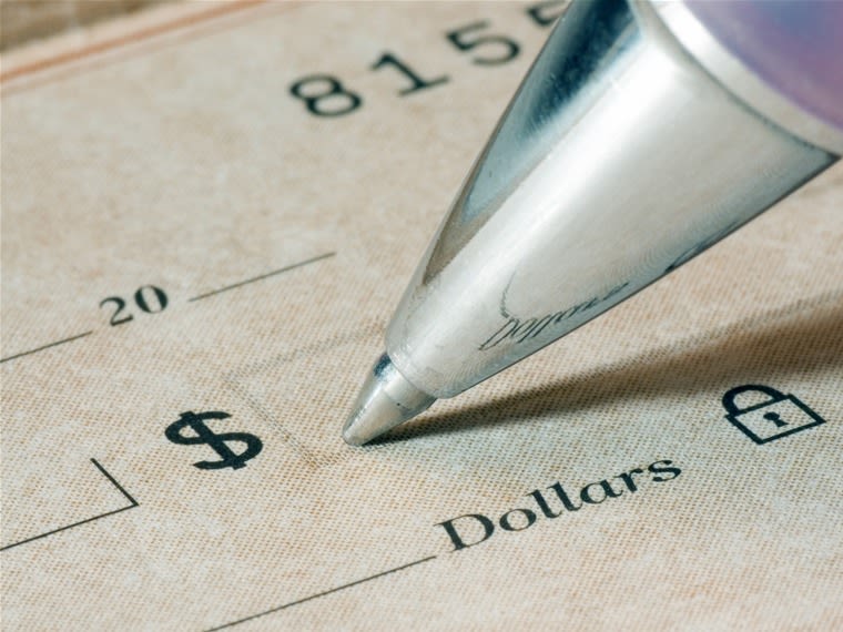 Close-up of a person filling out a dollar amount on a check, focus is sharp and on the pen tip and the dollar word and symbol.  check, finance, pen, w...