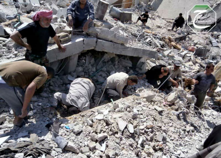 Residents of Qusair stand amid rubble after a Syrian military air strike. The town remains under siege.