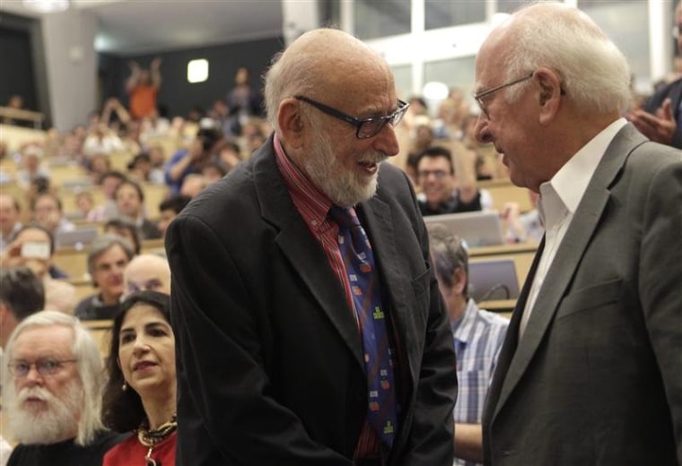 Belgian physicist Francois Englert (left) and British physicist Peter Higgs (right) shake hands before the scientific seminar that revealed the discovery of a
