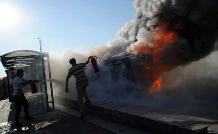 Men try to stop a police car from burning at Taksim Square in Istanbul, June 3, during protests against the Islamic-rooted government. Turkish Prime Minister Recep Tayyip Erdogan on Monday rejected talk of a
