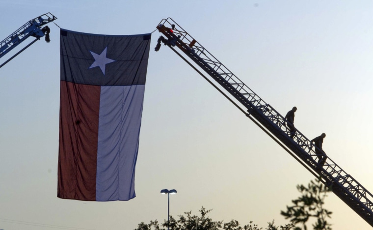 Firemen descend after hanging a Texas flag from ladder trucks before the memorial service in Houston.