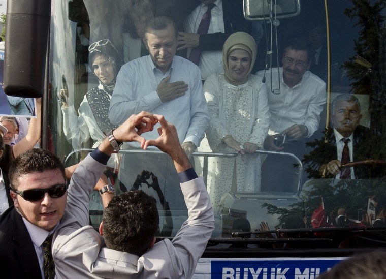 A man makes a heart shaped sign to Turkish Prime Minister Recep Tayyip Erdogan and his wife Emine to show support after his arrival in Ankara, Turkey, Sunday, June 9, 2013.