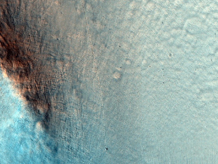 A lone boulder leaves a track in the Martian soil on a slope at Nili Fossae, as seen by the high-resolution camera on NASA's Mars Reconnaissance Orbiter.