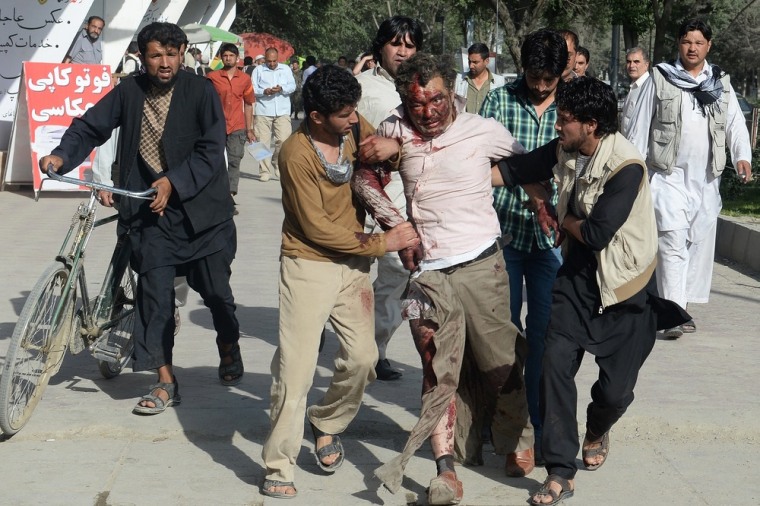 One of at least 38 people injured in a suicide blast is Kabul is helped from the scene. At least 14 are dead.