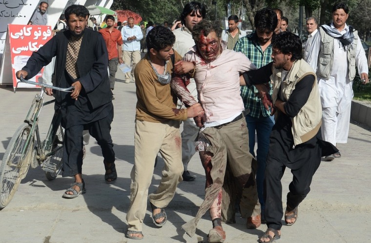 Afghan men assist an injured man at the site of a suicide attack in Kabul on June 11.