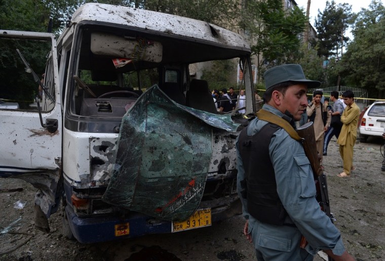 An Afghan policeman stands guard in front of a badly damaged bus at the site of a suicide attack in Kabul on June 11.