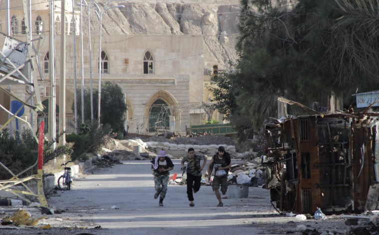 Members of the Free Syrian Army run to avoid a sniper in Deir al-Zor, June 13, 2013.