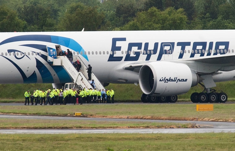 Police escort passengers off the Egyptair Boeing 777 flight from Cairo that was forced to land at Glasgow Prestwick airport in Scotland en route to JFK airport in New York.