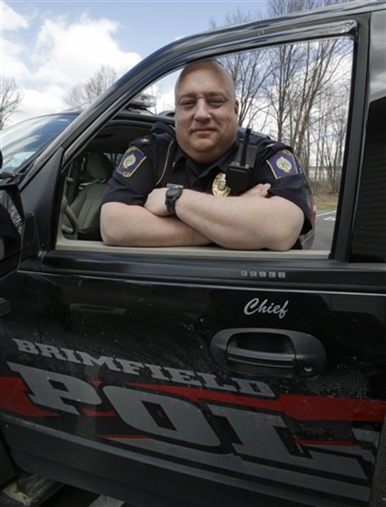 In this Tuesday, April 2, 2013 photo showing Brimfield Police Chief David Oliver posing by his police car in Kent, Ohio. Oliver uses the reach of his ...