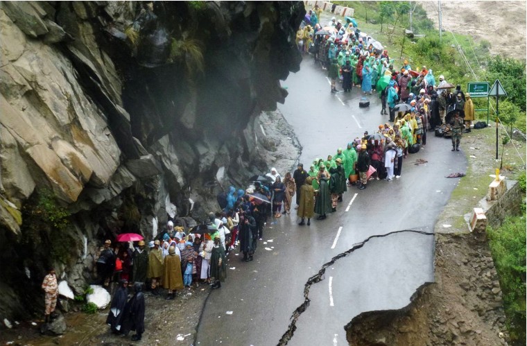 Indian security personnel supervise residents and travelers as they stand on the remains of a flood damaged road alongside the River Alaknanda in Chamoli district in the northern Indian state of Uttarakhand on June 18, 2013.