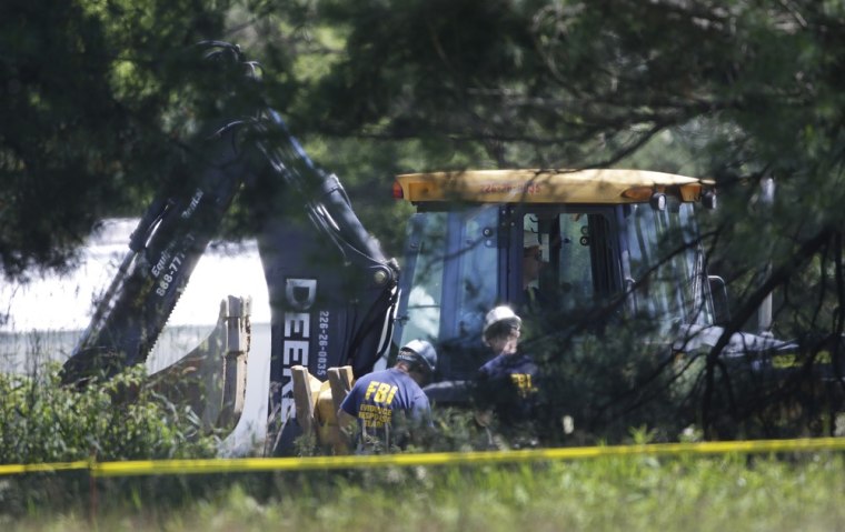 Members of an FBI evidence response team look over an area being cleared in Oakland Township, Mich., Tuesday, June 18, 2013 where officials continue t...