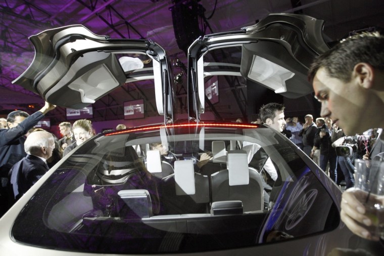 People look at the Tesla Motors Model X electric vehicle at its unveiling at the Tesla Design Studio in Hawthorne, Calif. in February 2012. The compan...