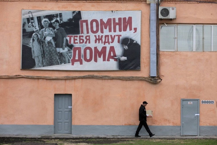 An inmate walks outside prison camp number 17 outside the Siberian city of Krasnoyarsk on May 14. The poster reads,