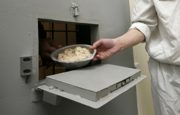 An inmate serves prisoners dinner inside a zone where especially strict conditions are imposed.