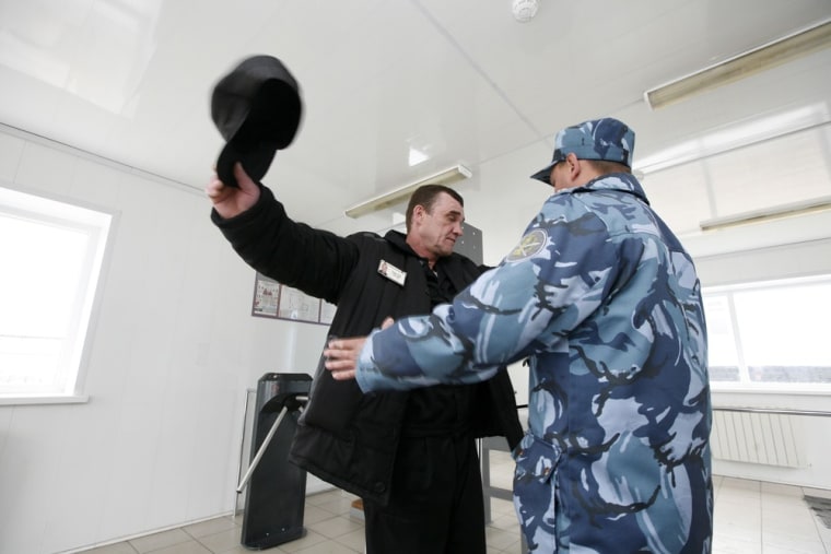 An officer searches an inmate at a control point between work and residential zones.