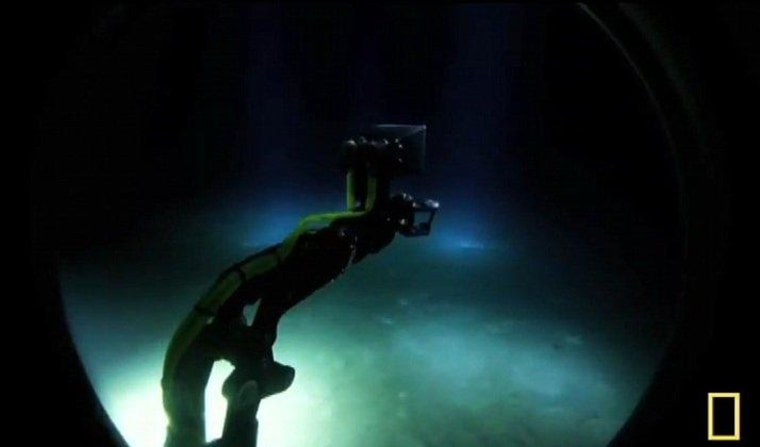 A video shot through a porthole of the Deepsea Challenger shows the submersible's robotic sampling arm sticking out over the