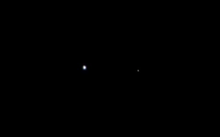 Earth is on the left and the moon is on the right in this Aug. 26 photo from the Juno probe.