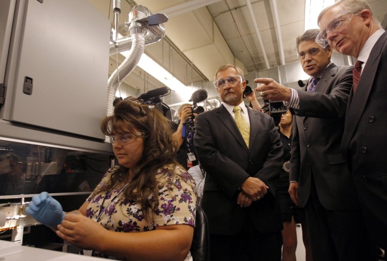 Texas Gov. Rick Perry extends his arm toward a lab worker during a tour of Resonetics Laser Micromaching in Nashua, N.H., on Wednesday. Resonetics CEO Chris Banas is to the left of Perry, and Cliff Gabay, the company's president, looks on from the right.