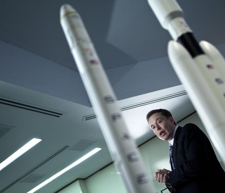 SpaceX CEO Elon Musk stands alongside rocket models at the National Press Club as he announces plans to build the Falcon Heavy rocket. Observers say the heavy-lift launch system could send an 11-ton payload to Mars.