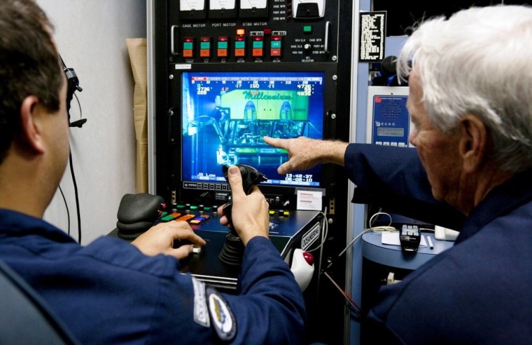 Pilots watch a video screen and control a  submersible vehicle in the Gulf of Mexico using a joystick and other control devices.
