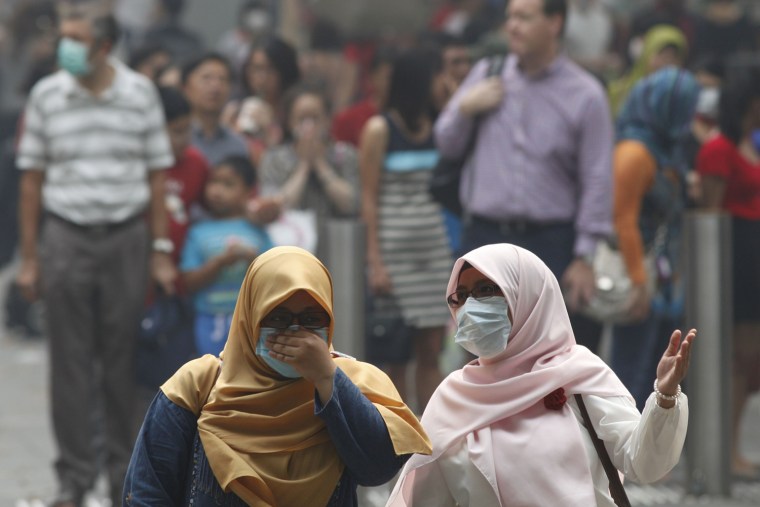 Women wearing masks chat as they cross a street in Singapore's Orchard Road Shopping Area June 21, 2013.