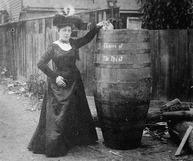 Annie Edson Taylor stands next to a huge barrel which bears the writing
