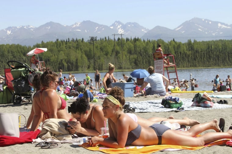 This photo taken Monday, June 17, 2013, shows people sunning at Goose Lake in Anchorage, Alaska. Parts of Alaska are setting high temperature records as a heat wave continues across Alaska. Temperatures are nothing like what Phoenix or Las Vegas gets, but temperatures in the 80s and 90s are hot for Alaska, where few buildings have air conditioning. (AP Photo/Mark Thiessen)