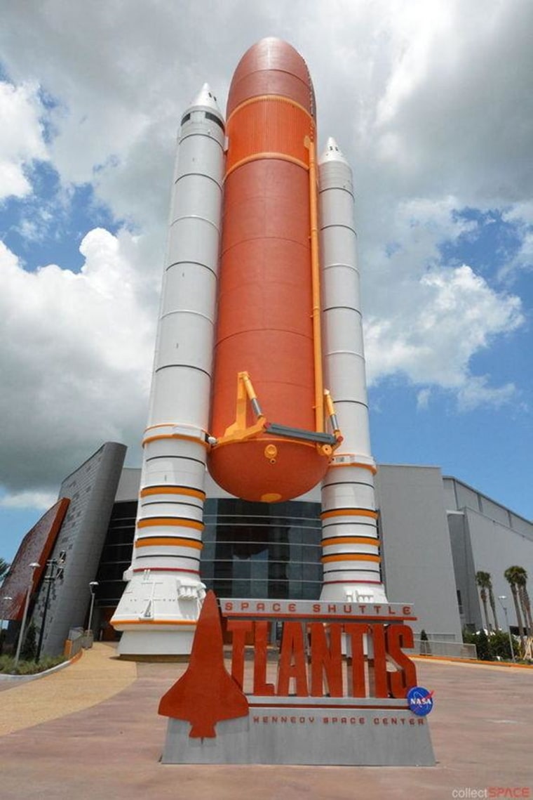 The gateway into the Atlantis exhibit, a 184-foot-tall replica of the shuttle's solid rocket boosters and external tank, establishes the scale for the orbiter's display waiting inside.