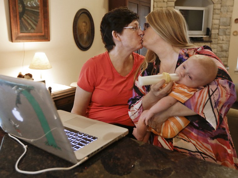 Julia Tate (left) kisses her wife, Lisa McMillin, while holding their son, Luke, as they read results of the Supreme Court decisions in an intimate moment at their home in Nashville, Tenn. One of the decisions ensures that married same-sex couples cannot be denied federal benefits like Social Security and family leave.