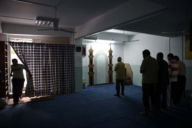 A man enters a makeshift mosque where others Muslim faithful pray at Kallithea suburb in Athens on May 22, 2013.
