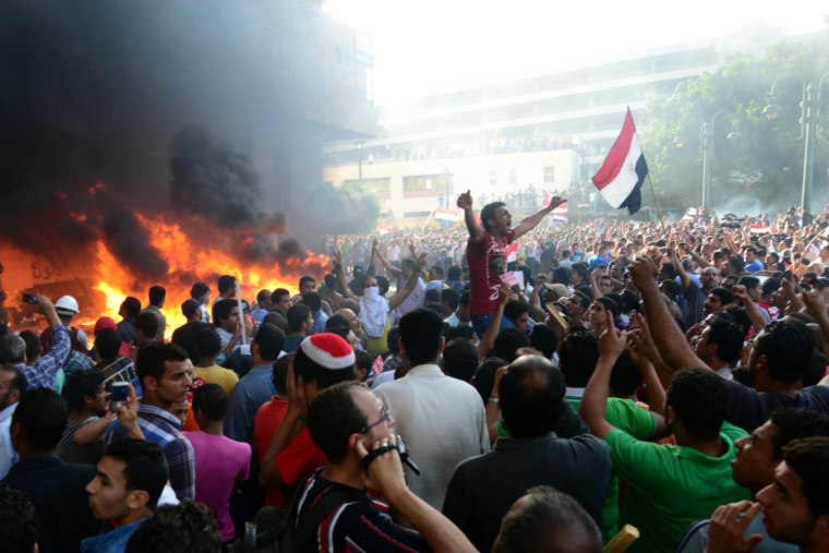 Opponents of Egypt's Islamist President Mohammed Morsi chant slogans as fire rages at the Muslim Brotherhood headquarters in Alexandria, on June 28, 2013.