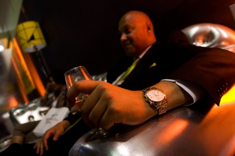 The wristwatch of a man is seen as he holds a glass of wine in his hand in Johannesburg.