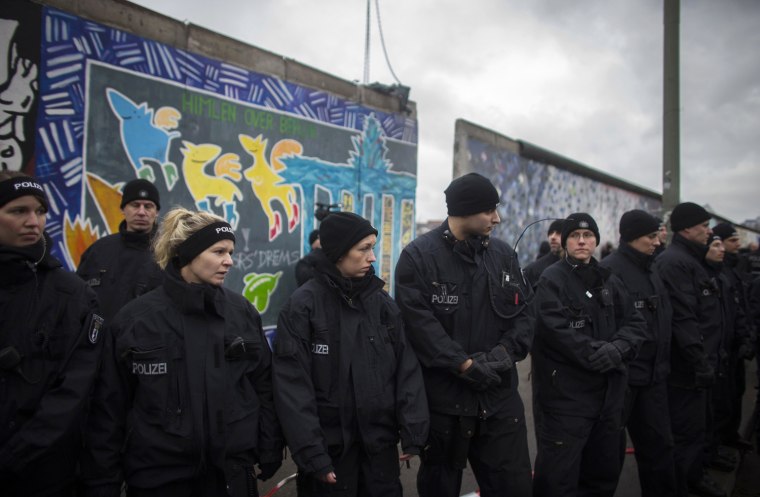Police keep watch as workers remove a piece of the former Berlin Wall, now known as East Side Gallery, in Berlin on March 1, 2013.