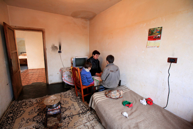 Teacher Liljana Luani, center, gives a weekly lesson to children whose family is forced to live in isolation in northwestern Albania, Jan. 18, following a murder conflict.
