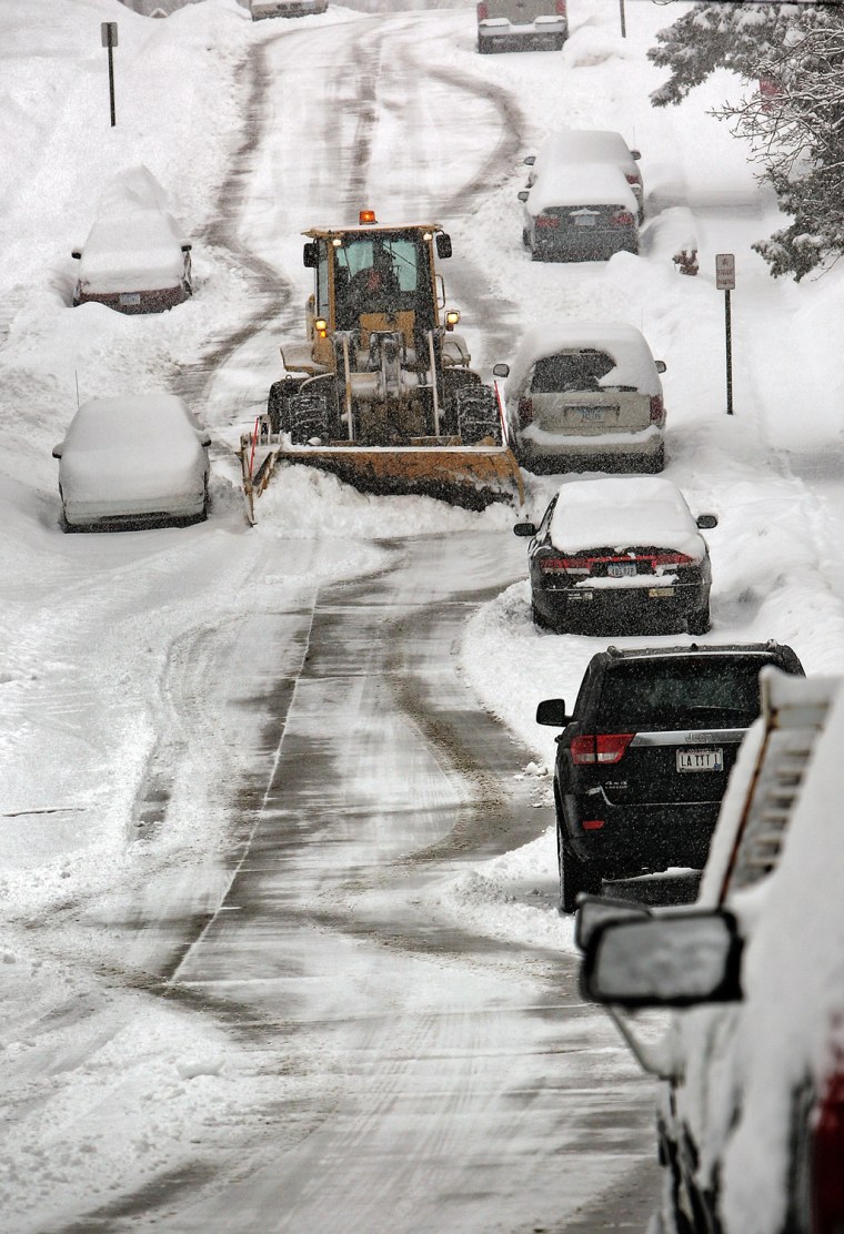 A snow plow slowly navigates around parked cars along West 3rd Street in Dubuque, Iowa during a snow storm Tuesday March 5. Forecasters say more snow is on the way to snarl travel and disrupt people's daily routines.