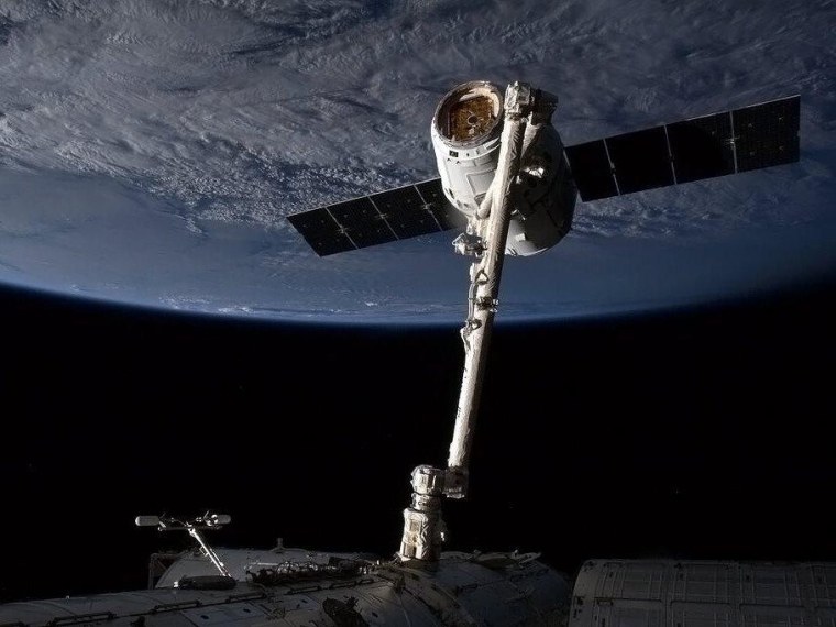 SpaceX's Dragon cargo capsule is held by the International Space Station's Canadian-built robotic arm in advance of its berthing on Sunday.
