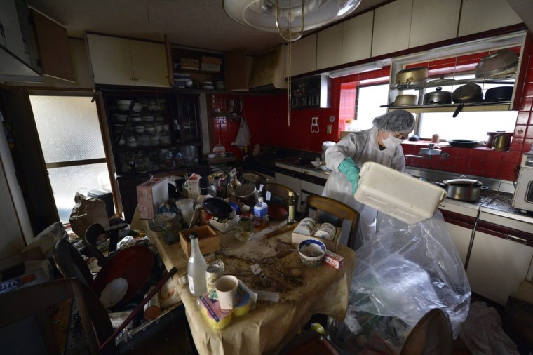 Yuko Mihara cleans her kitchen, which is covered with debris and putrefied food.