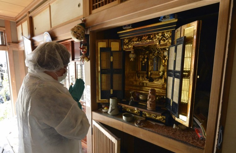 Yuko Mihara offers prayers to her ancestors in front of a family Buddhist altar inside her house.