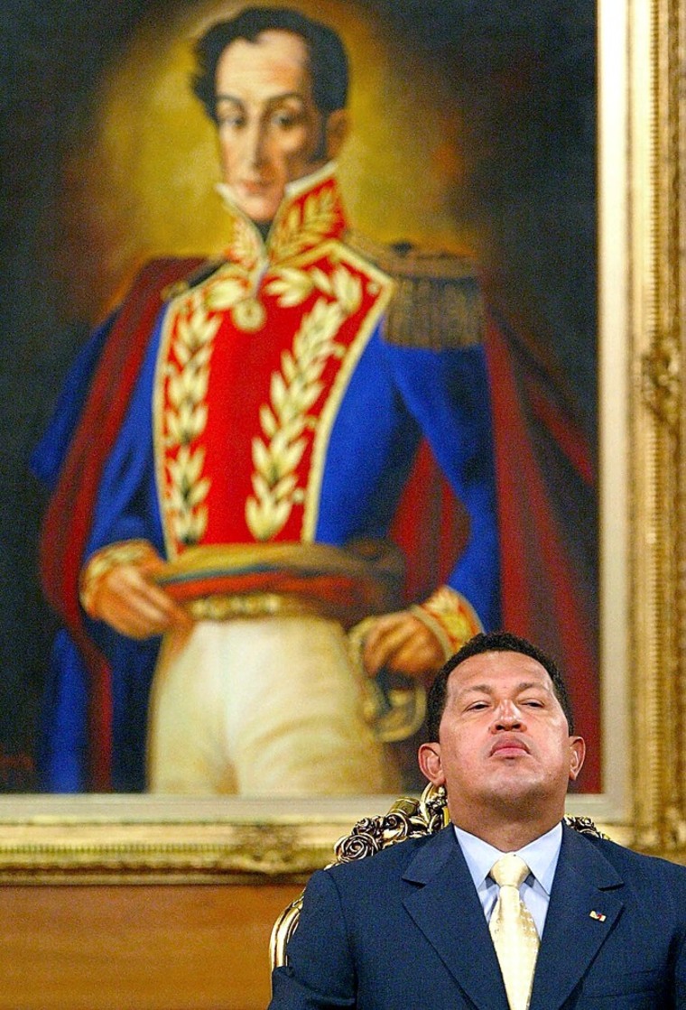 Venezuelan President Hugo Chavez sits under a portrait of his hero Simon Bolivar during a press conference in Caracas in Sept. 2002.