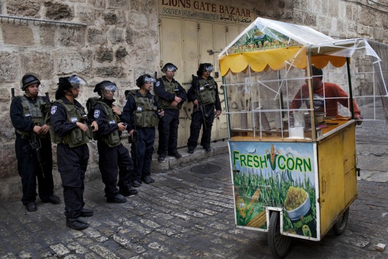 A Palestinian street vendor walks past Israeli security forces in Jerusalem's Old City on March 8, 2013.