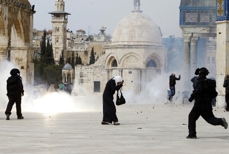A Palestinian woman covers her face as a stun grenade fired by Israeli police explodes nearby during clashes in Jerusalem's Old City on March 8, 2013.