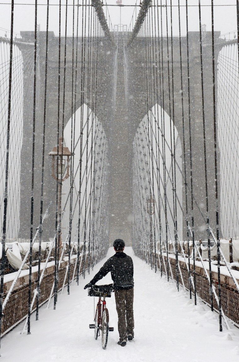 A man walks his bicycle across the Brooklyn Bridge during a snow storm in New York City, on March 8.
